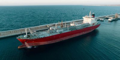 aerial-view-of-a-massive-red-cargo-ship-docked-at-a-coastal-port-under-clear-skies-xtqDZ_I_Cxy-bu0CjfH3iA